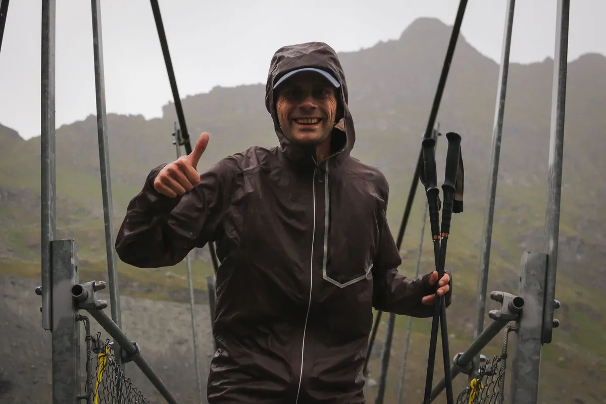 Nicolas Goullet de Rugy sous la pluie sur une passerelle de l’UTMB Verbier, ses bâtons Kiprun carbone à la main